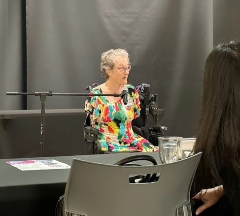 A woman in a power wheelchair speaking at a training event